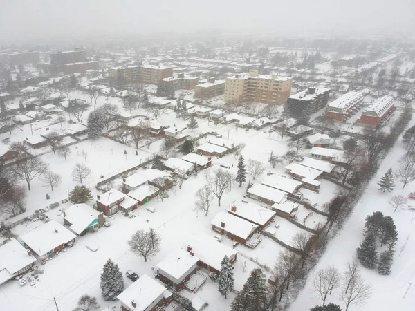 High level of snow storm, winter weather forecast alert day in the city. Top aerial view of people houses covered in snow, bird eye view suburb urban housing development. Quite neighborhood, Canada.