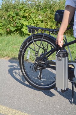 Pil paketi e bisikletini yakınındaki Elektrikli bisiklet tutan kadın. 