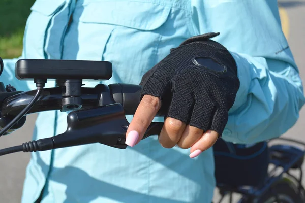 Vrouw hand met helder roze nagels op het handvat van de elektrische fiets — Stockfoto