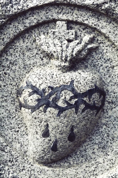 Sacred heart medallion with crown of thorns and blood in stone.