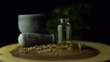 Kenevir bitkisinin biyolojik ve ekolojik yağını damlatan makro yakın plan. Ahşap çemberin üzerindeki küçük kavanozdaki bitkisel cbd yağı. Organik ilaç konsepti.