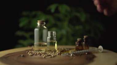 Eczacı ya da eczacının eczacılık CD 'si yağında çalışan bilim adamına yakından bakın. Ağız kullanım için kavanozlardaki haplar ve yağlar gibi ahşap masada çeşitli ilaç seçenekleri var. Kenevir bitkisi.