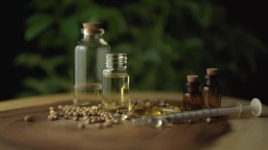 Kenevir bitkisinin biyolojik ve ekolojik yağını damlatan makro yakın plan. Ahşap çemberin üzerindeki küçük kavanozdaki bitkisel cbd yağı. Organik ilaç konsepti.