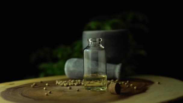 Macro cerrar y rotación girando de aceite de cbd a base de hierbas en el pequeño frasco en la mesa de anillo de árbol de círculo de madera con mortero, pestle y semillas de cáñamo. Legalización del concepto de medicalmarihuana . — Vídeo de stock