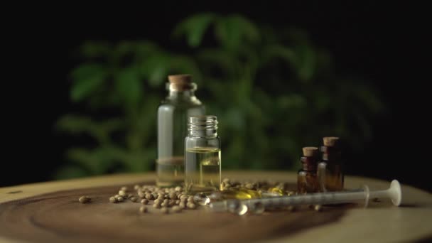 Pečlivý pohled na rotaci nebo spřádání farmaceutických lékařských cbd olejů a léků. Různé možnosti medicíny na dřevěném stole, jako pilulky a oleje ve sklenicích pro perorální použití. Konopná rostlina. — Stock video