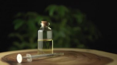 Kaygı ve stres için kullanılan Cbd yağı ve ağız şırıngası çok yakından görülüyor. Ağaç halkası masasındaki cam kavanozun yanında. Dalgalanma çizgisi desenli. Acı tedavisinde ve iyileşmede devrim.