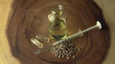 Cbd yağı, ağız şırıngası, anksiyete hapları ve ağaç halkası masasındaki cam kavanozun yanında dalgalanma çizgisi desenli stres giderici haplar. Acı tedavisinde ve iyileşmede devrim.
