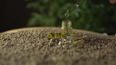 Pipette damlaları cbd yağı içerken kayıyor ve odaklanıyor. Kenevir tohumlarının üzerinde cam kavanoz. Yeni nesil sağlık eczanesi tıbbi konsepti. Acı tedavisinde devrim ve iyileşme endişesi.