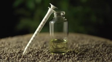 Kenevir tohumu ve yeşil marihuana bitkisi arka planında tıbbi marihuana CBD yağı ve ağız şırıngası var. Odaklan ya da yana kay. Acı tedavisinde ve iyileşmede devrim.