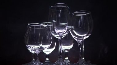 Şarap için farklı şekilli boş bardakları olan gece kulübü tezgahı, arka planda sis ile barda ağır çekimde dönen. Noel ya da yeni yıl partisi konsepti. Kapat..