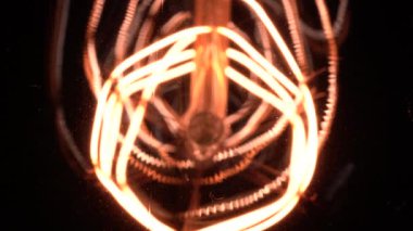 Edison ampulünün içindeki ekstrem makro ışık yavaş yavaş odak ve ayrıntıları açığa çıkarıyor. Vintage filament ampulün altında kayarak bokeh etkisi ile aşağıdan yakın görüntüyü parlaklaştırır. 4k.