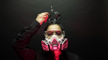 Coronavirus pathogen outbreak pandemic biohazard concept. Woman in heavy duty urban protective air mask and glasses put the crown on the head. Virus disease 2019-nCoV or covid-19 protection. 4k
