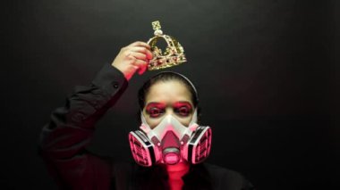 Woman in the heavy duty biohazard medical mask put the crown or corona on the head. Personal forced home quarantine isolation from Coronavirus or covid 19 concept. Apocalypses and depression mood.