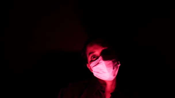 Femme dans le masque médical chirurgical dans l'obscurité et la lumière rouge. Isolement personnel en quarantaine forcée du Coronavirus ou concept de covidé 19. Apocalypses et humeur dépressive de l'épidémie mondiale . — Video