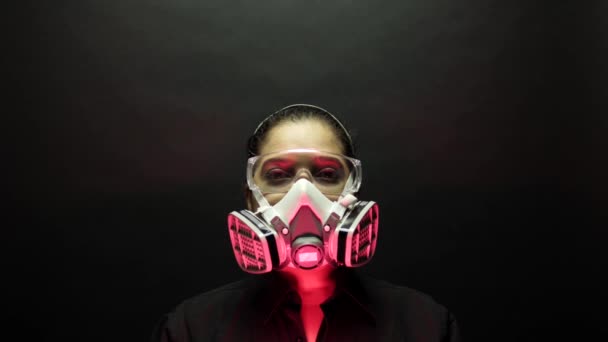 Концепция пандемической биологической опасности вспышки коронавируса. Женщина в тяжелой городской защитной маске и очках, смотрящая на камеру на черном фоне. Вирусная болезнь 2019-nCoV защиты. 4k — стоковое видео