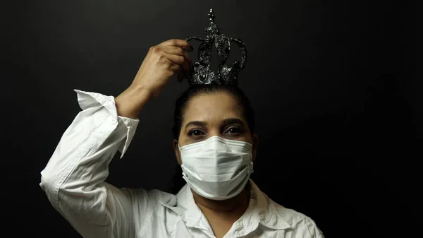 Woman in surgical or medical mask put on the crown on the head, — Stock Photo, Image