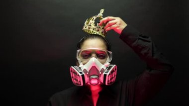 Coronavirus pathogen outbreak pandemic biohazard concept. Woman in heavy duty urban protective air mask and glasses put the crown on the head. Virus disease 2019-nCoV or covid-19 protection. 4k