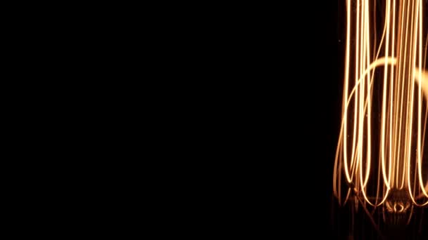 Лампа лампы накаливания Эдисона с вольфрамовой нитью становится ярче и движется качаясь в то время как спинниг. Жёлтый свет поверх чёрного фона, вид поближе. Отправка подробностей из Бокэ, 4k. — стоковое видео