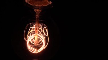 Edison ampulü yavaş yavaş odak ve detaylarla ortaya çıkar. Vintage filament ampulün altında kayarak alttaki makro görüntüyü bokeh efektiyle parlıyor ve parlatıyor. 4K.