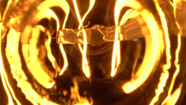 マクロのエジソン電球の内部で、黒い背景か闇の中で、近くの眺めをゆっくりと滑ります。タングステン電球ランプ素子とガラスの詳細は、ゆっくりと光効果ボケから明らかにする。トップ表示. — ストック動画