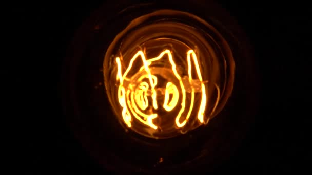 Медленное скольжение внутри лампочки Эдисона в макро-близком обзоре, на черном фоне или в темноте во время мерцания. Вольфрам лампы элементов лампы и стекло детали медленно раскрывает в затемнение. Вид сверху. — стоковое видео