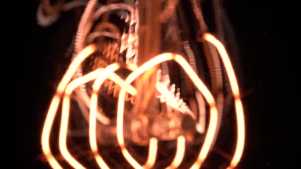 Movimento câmera lenta em macro revelar detalhes nítidos em parte da lâmpada de tungstênio ou lâmpada Edison. Vista acolhedora sobre fundo preto, macro close-up de luz vintage retro velho. 4k. — Vídeo de Stock