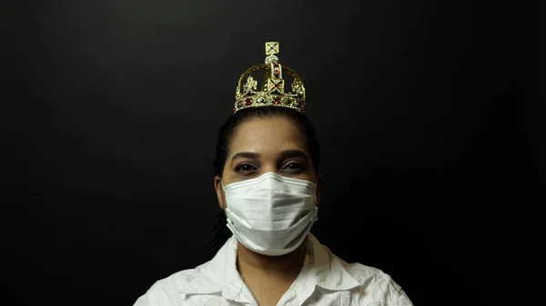 Woman in surgical or medical mask put on the crown on the head, depicting Coronavirus or covid 19, virus outbreak concept. Corona virus disease 2019-nCoV protection and prevention.