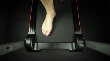 Çıplak ayak koşu bandında koşan bir adam. Spor salonunda ya da spor salonunda yürüyüş, spor malzemeleriyle kardiyo çalışması. Ofiste geçirdiğim uzun bir günden sonra spor kulübünde rehabilitasyona gittim..