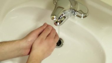 Ellerini sabun tuğlasıyla köpürten ve beyaz banyo lavabosunda durulanan bir adama yaklaş. Sağlık ve vücut bakımı kavramı. COVID 19 veya Coronavirus 2019 nCoV enfeksiyonunun kişisel önlenmesi.