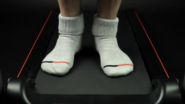 Vista frontal de las piernas del hombre en los calcetines lombrando y ejercitando las articulaciones cerca de los pies antes de correr en la cinta de correr para el entrenamiento cardiovascular. Cerca de las piernas en el gimnasio de la oficina . — Vídeo de stock