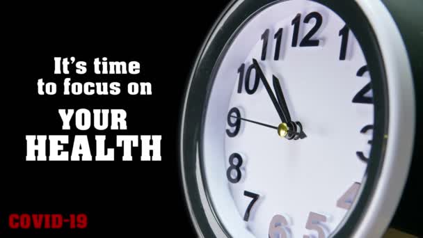 Clock dial close-up met COVID-19 pandemische quote: Het is tijd om je te concentreren op je gezondheid. Tafelbedrijf timer gezicht tijd verval. Quarantaine tijd en zelfisolatie voor familie Coronavirus concept. 4k. — Stockvideo