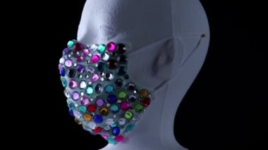 Kadın, virüslerden ve tozdan korunmak için tıbbi açıdan lüks mücevher maskeler takan mankenlerle karşı karşıya. Yavaşça dönüyor. Kentsel maske konsepti ve hava yoluyla bulaşan bakteri ve mikroplardan korunma.