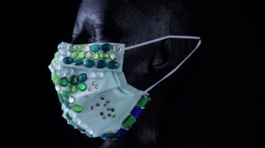 Kadın, virüslerden ve tozdan korunmak için tıbbi açıdan lüks mücevher maskeler takan mankenlerle karşı karşıya. Yavaşça dönüyor. Kentsel maske konsepti ve hava yoluyla bulaşan bakteri ve mikroplardan korunma.