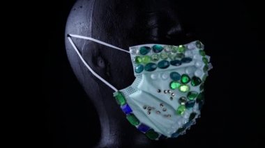 Kadın, virüslerden ve tozdan korunmak için tıbbi açıdan lüks mücevher maskeler takan mankenlerle karşı karşıya. Yavaşça dönüyor. Kentsel maske konsepti ve hava yoluyla bulaşan bakteri ve mikroplardan korunma.