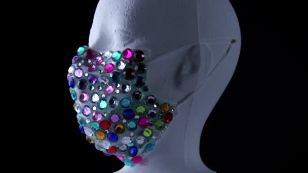 女性面对人体模特身穿时尚的医疗奢侈品宝石面罩，以抵御病毒和灰尘，慢慢旋转。城市面罩的概念和对空气中细菌和细菌的预防. — 图库视频影像