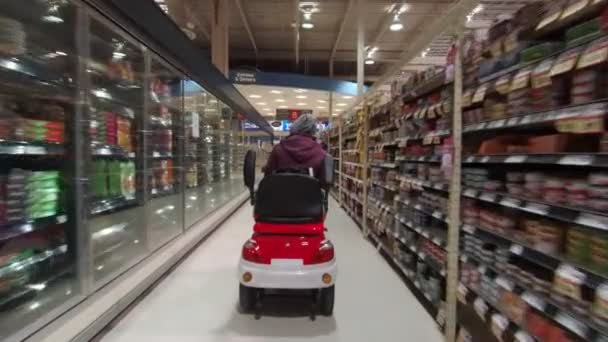 Toronto, Ontario, Canadá - 7 de abril de 2020: Mujer discapacitada en el scooter de movilidad en la máscara médica y guantes de compras en la tienda de comestibles durante el brote pandémico de coronavirus COVID-19 . — Vídeos de Stock