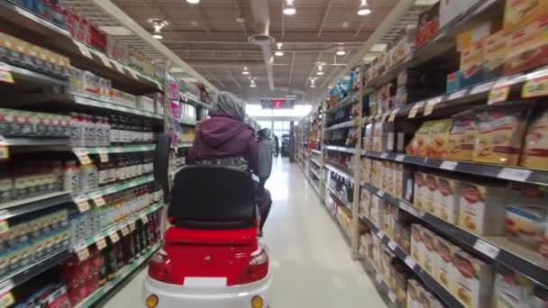 Toronto, Ontario, Kanada - 7 april 2020: Funktionshindrad kvinna på mobilitetsskotern i den medicinska masken och handskar shopping i livsmedelsbutiken under coronavirus COVID-19 pandemiutbrott. — Stockvideo