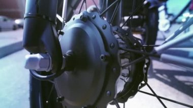 Keskinlikten bulanık tekerleğe ve aşağıdaki elektrikli bisiklet manzarasının motoruna kadar görüntülenir. E motorlu kamera hareketi yaklaşıyor. Otoparktaki doğal ışıklandırmayla.