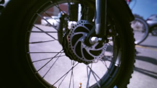 Från skarp till suddig hjul och motor av den elektriska cykelvyn underifrån visas. E cykel motor kamerarörelse glider närbild. Med naturlig belysning på parkeringen. — Stockvideo