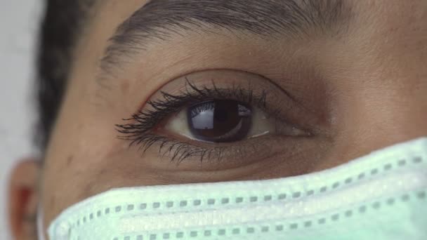 캐나다 간호사가 코로나 바이러스 (COVID-19 coronavirus) 가 유행하는 동안 마스크를 쓰고 있다. 병원 과 요양원에서 필수적 인 서비스를 제공 한다. 눈 가까이에 있는 극도의 매크로. 일회용 마스크를 쓴 여자. — 비디오