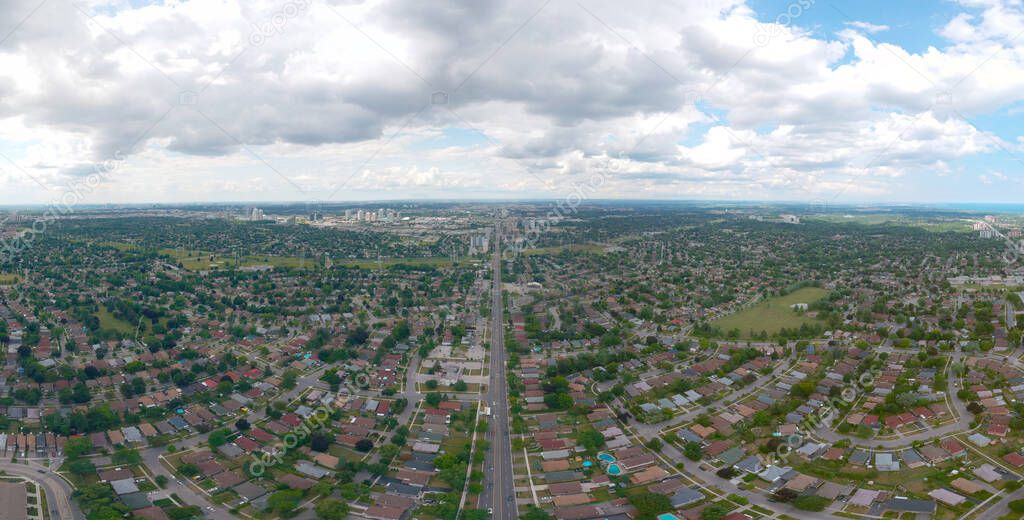 Artistic view of Toronto city at cloudy sky day. Panoramic summer landscape in  Ontario, Canada. North American urban commuter background of houses, stores, parking, and roads with green trees. 