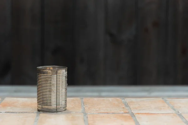 Lata de lata no chão de telha de argila — Fotografia de Stock