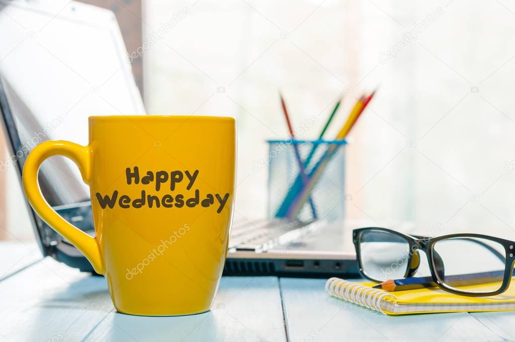 Happy Wednesday word on yellow morning coffee cup at blurred home or office background