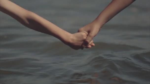 Два хлопчика, тримаючись за руки в море — стокове відео