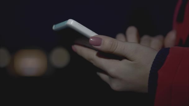 Woman hands using mobile smart phone with colorful light bokeh background - close up — Stock Video