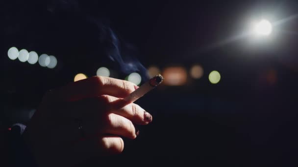 Flicka hand hållande en cigarett medan rökning på natten — Stockvideo