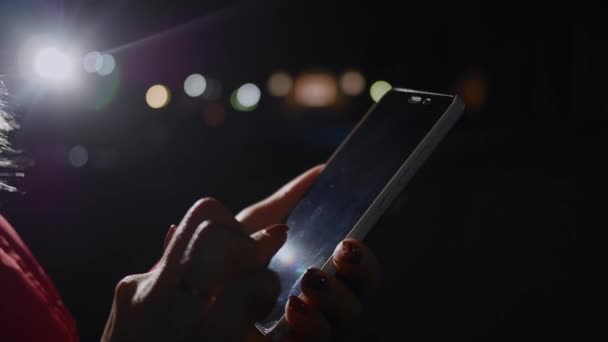 Les mains de la femme en utilisant un téléphone intelligent mobile avec fond bokeh lumière colorée - gros plan 