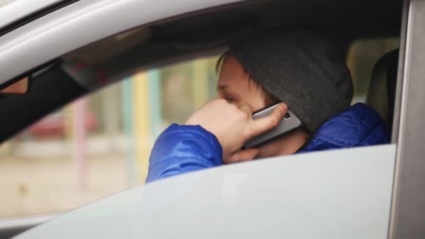 Homem a falar ao telemóvel no carro estacionado. Vista através do pára-brisas . — Vídeo de Stock