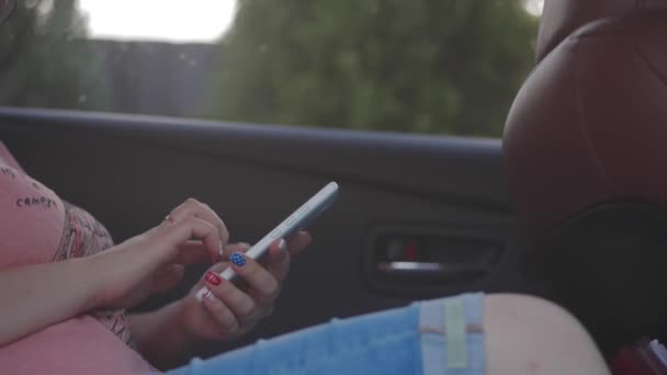 Chica escribiendo en un teléfono móvil en el coche — Vídeos de Stock