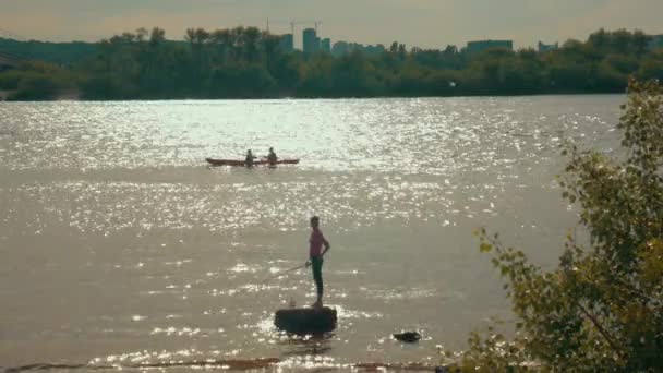 A girl at sunset fishing for a city background — Stock Video